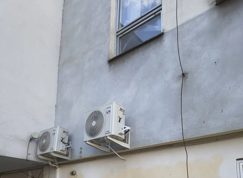 Venkovní jednotky Sinclair na konzolách pod oknem na fasádě